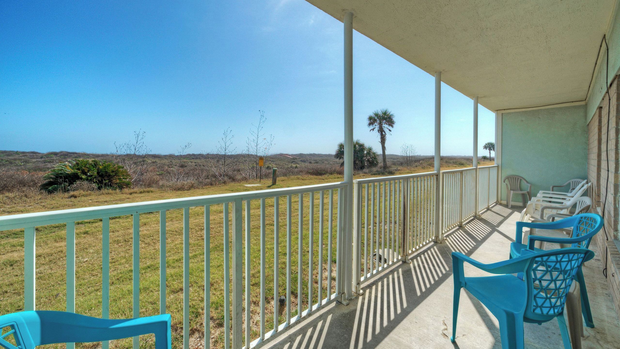 A balcony with a view of a grassy landscape and a clear sky.