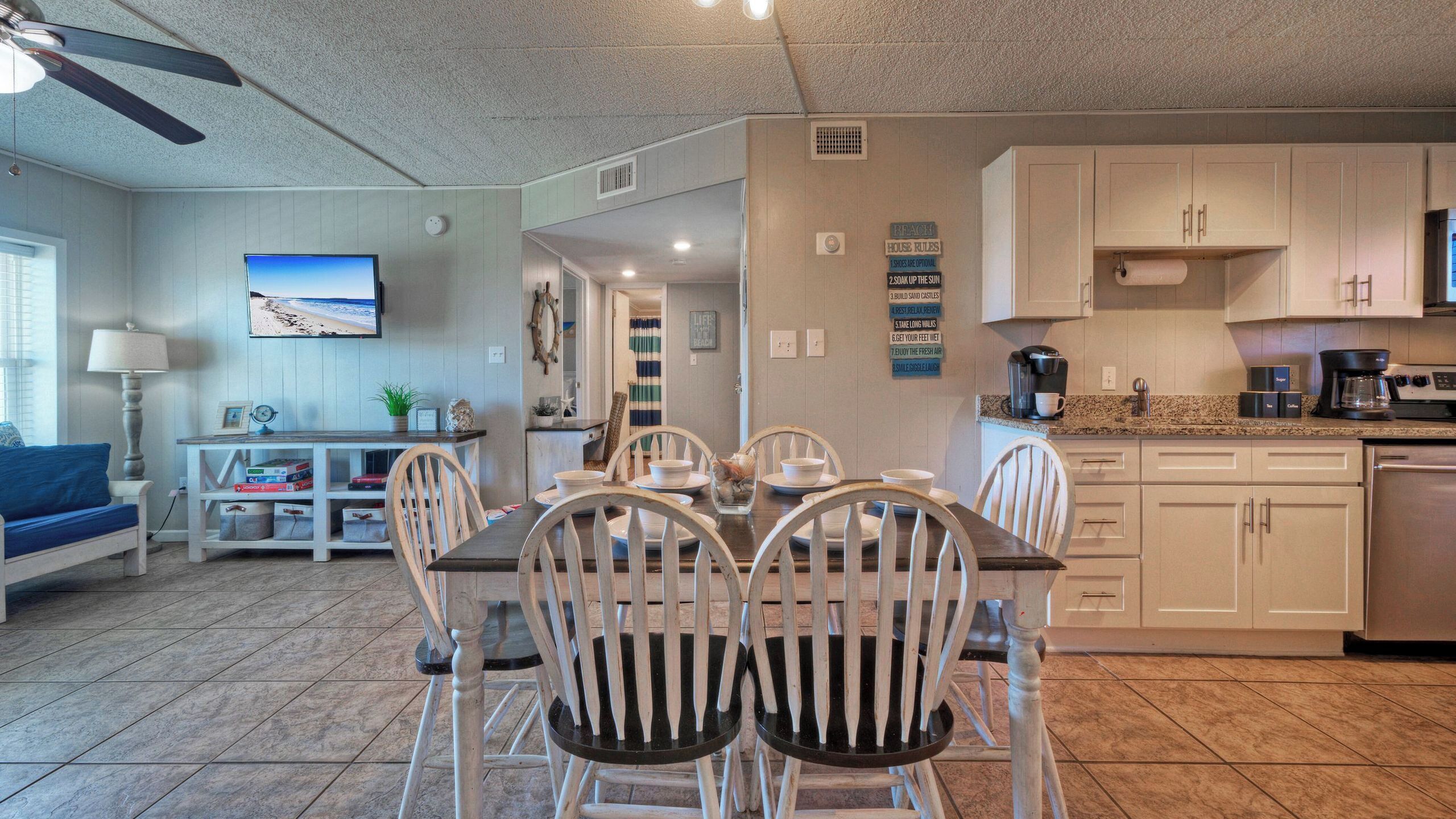 A dining area with a table and chairs, a television, and a kitchen with cabinets and appliances.
