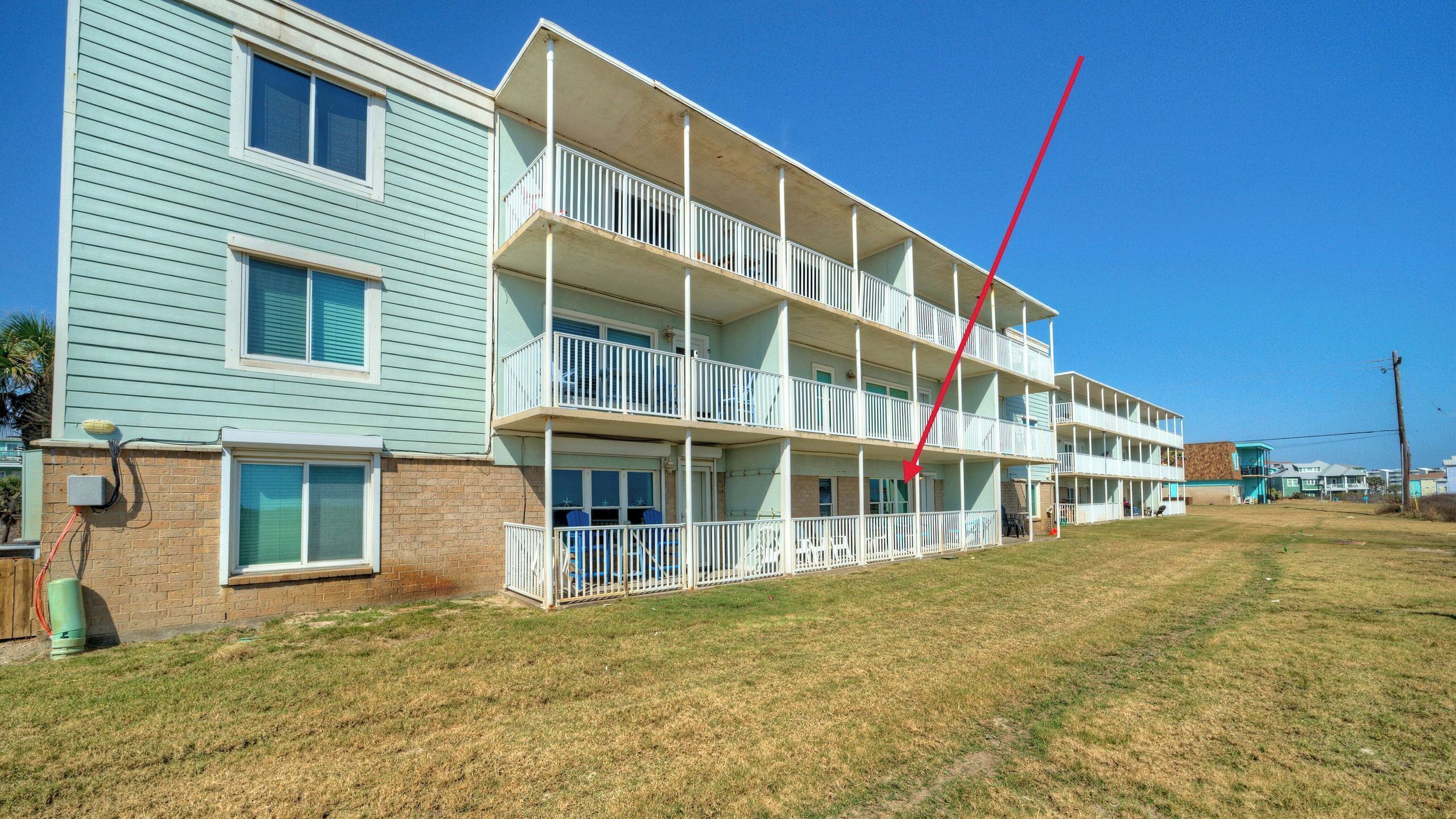 A multi-story motel with a flat roof, balconies, and a grassy lawn.