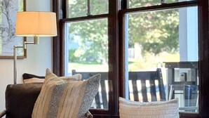 Ein gemütliches Wohnzimmer mit einem dunkelbraunen Ledersofa, einem runden Couchtisch und einer Fensterbank mit Kissen.