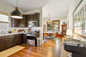Una cocina moderna con armarios de madera oscura, electrodomésticos de acero inoxidable y un comedor con mesa y sillas de madera.