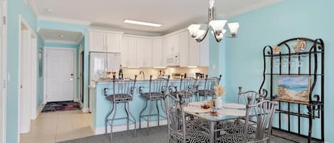 A dining area with a table set for four, surrounded by chairs with patterned cushions.