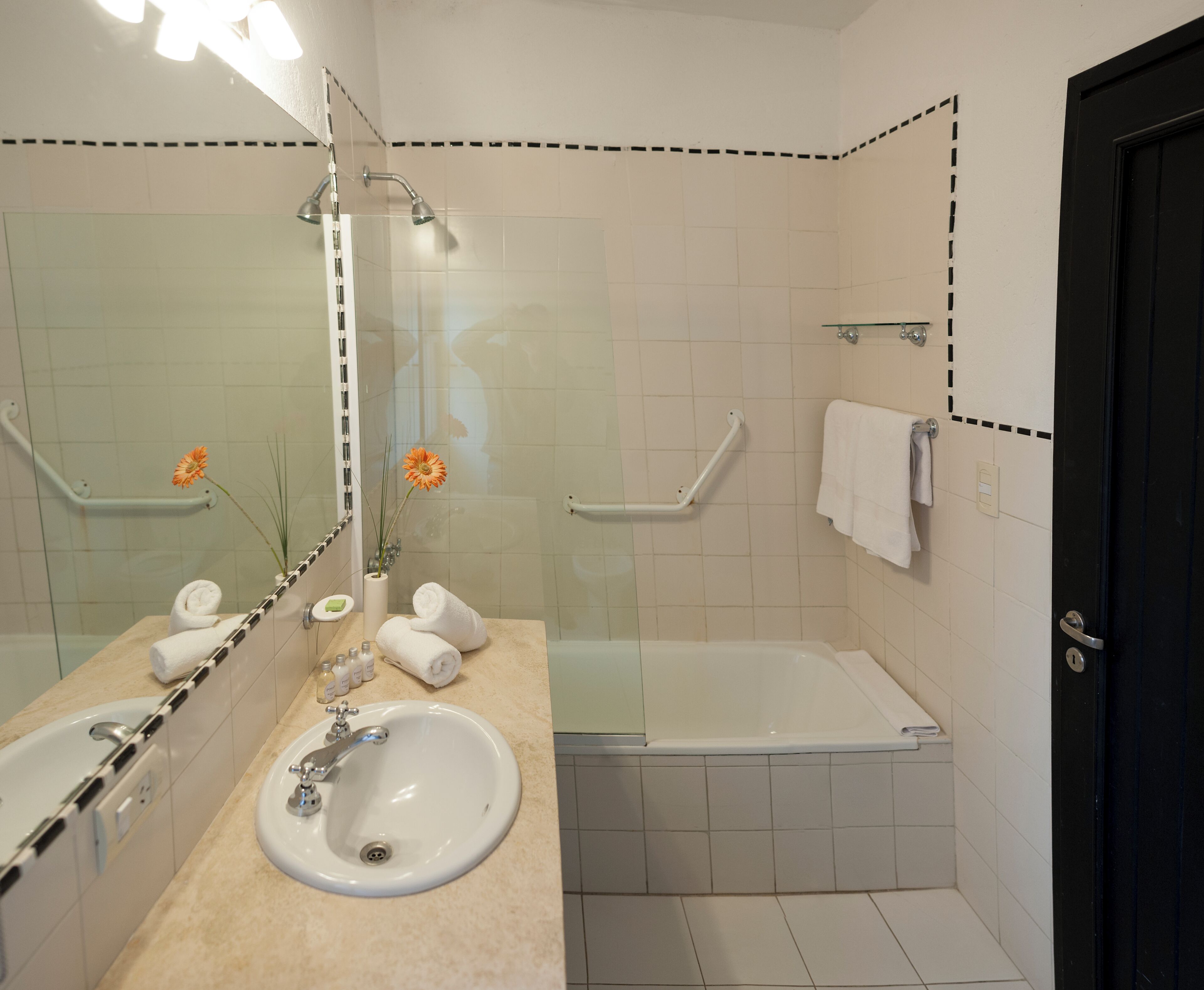A bathroom with a sink, mirror, shower, and bathtub.