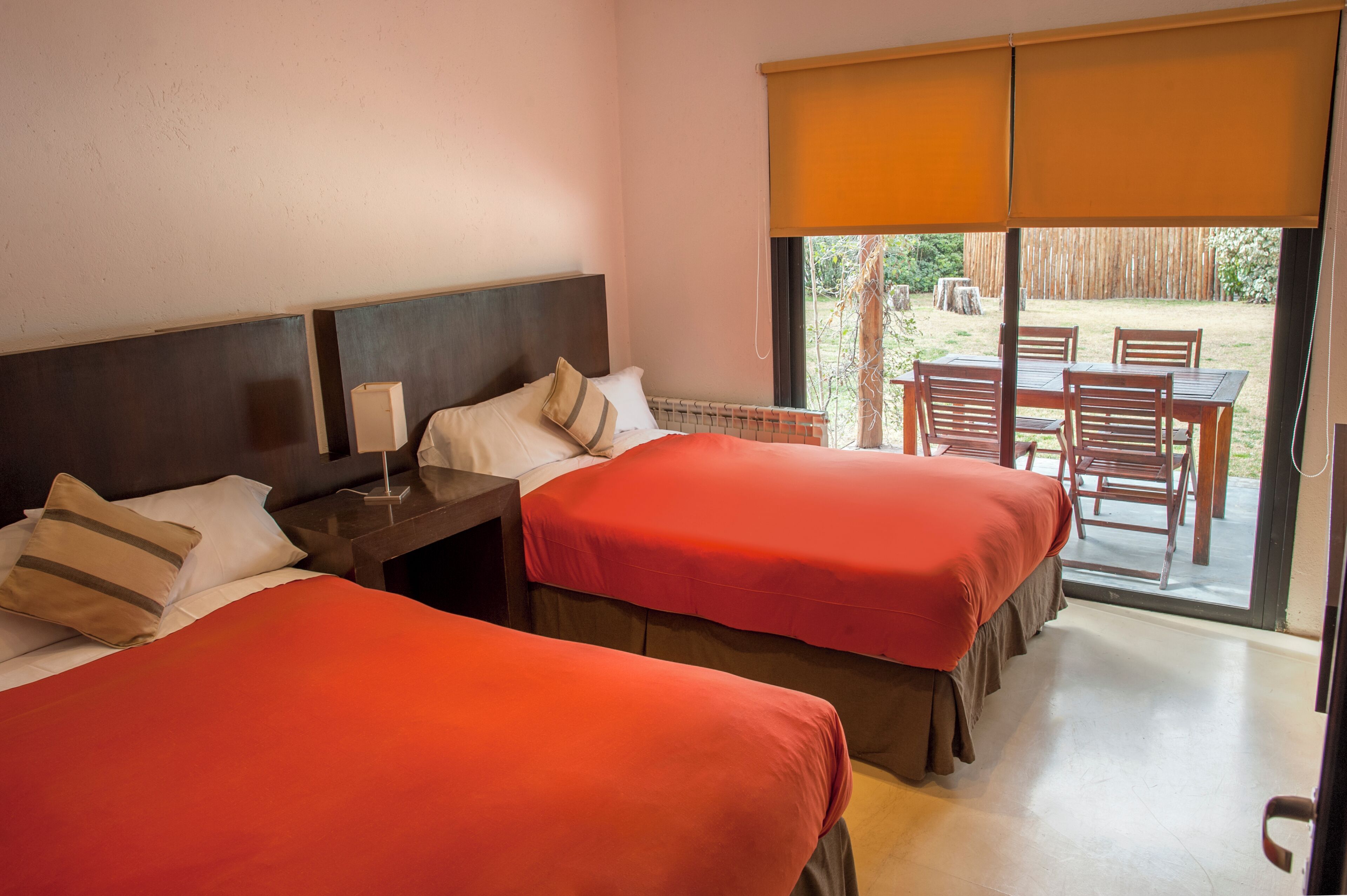 A hotel room with two beds, a nightstand, and a view of the outdoor patio.
