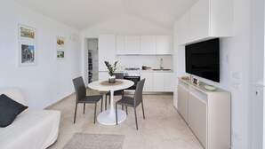En kompakt bolig med tekøkken, spiseplads og fjernsyn ophængt på væggen.