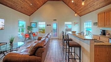 A spacious interior with a high ceiling, a dining area, a kitchen, and a seating area with a leather couch.