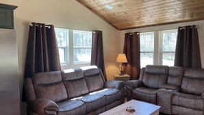 Ein Wohnzimmer mit zwei braunen Ledersofas, einem Holztisch und einer Lampe auf einem Beistelltisch.