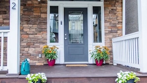 A house with a stone facade, a gray front door, and a porch with steps leading to the entrance. - Spacious 5BR Home | Great for Groups & Families (Pittsburgh)