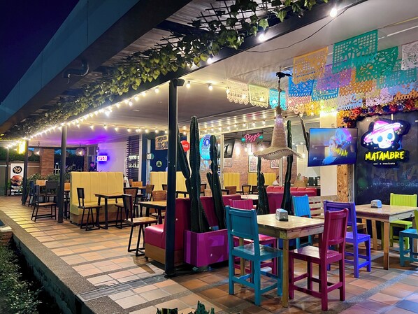 An outdoor dining area with colorful seating and a pizza sign.