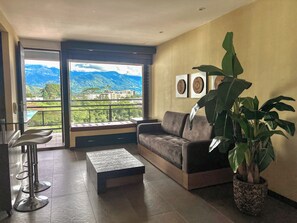 A modern living room with a sofa, a coffee table, and a large potted plant.