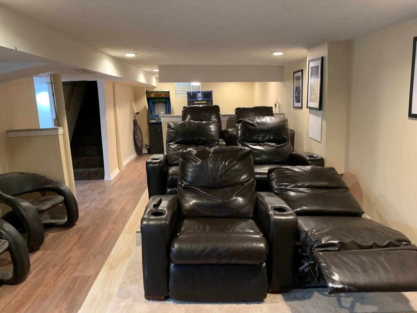 Una habitación con varios sillones de cuero, una mesita y un televisor.