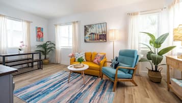 Uma sala de estar com sofá, poltrona, mesa de centro e um quadro na parede.