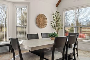 Spiseområde med et bord, stole, en potteplante og et vægtæppe på væggen.