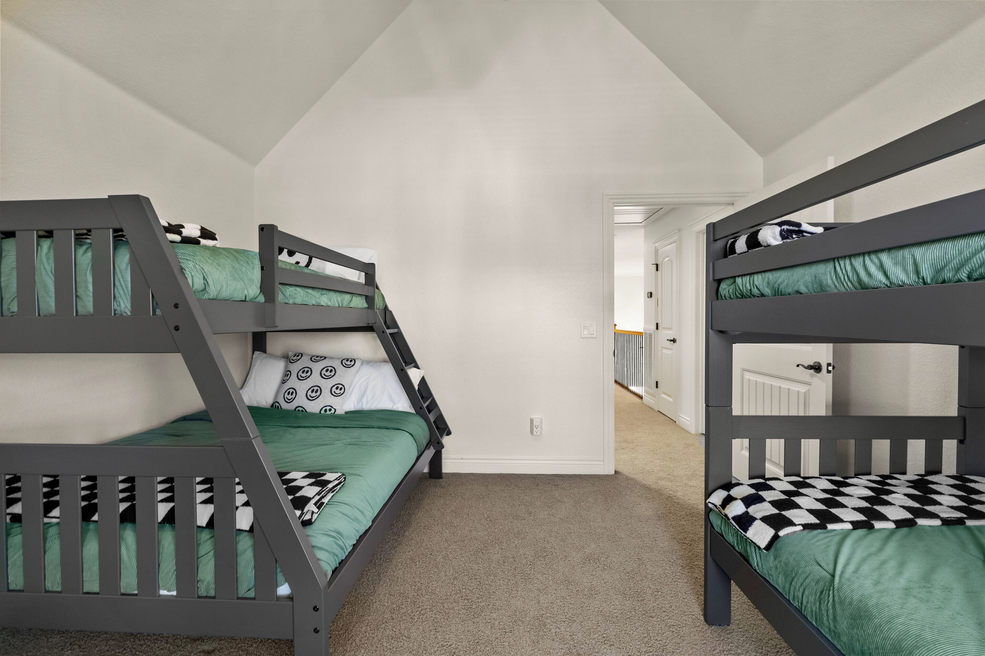 Ein Zimmer mit zwei Etagenbetten, Teppichboden und einer weißen Tür im Hintergrund.