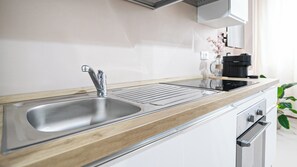 A modern kitchen with a stainless steel sink, wooden countertop, and built-in oven. - Giulini 5 - A - One Bedroom Apartment, Sleeps 3 (Monza)