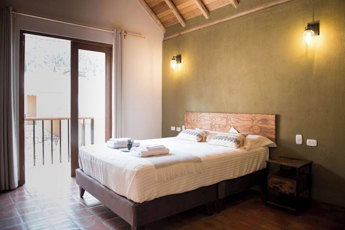 A bedroom with a large bed, a wooden headboard, and a balcony with a railing.