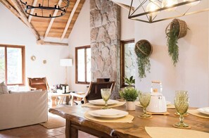 A dining area with a wooden table set for four, surrounded by chairs, a sofa, and a fireplace. - Killay by Wynwood House (Calca)