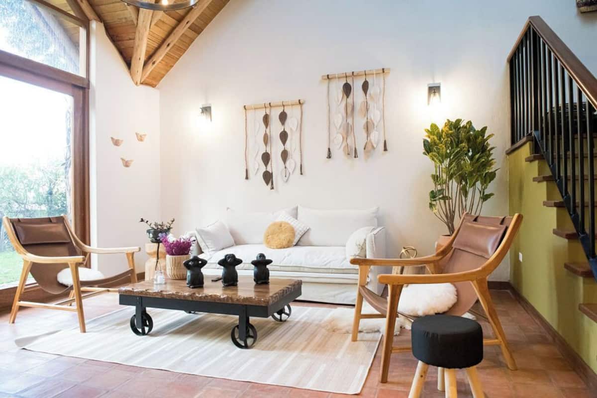 A modern living room with a sofa, two chairs, a coffee table, and wall art.