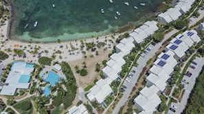 An aerial view of a coastal resort with a swimming pool, beach, and multiple buildings with solar panels. - New High End Rental At Cowpet Bay! Amazing Views/Breezes! (East End)
