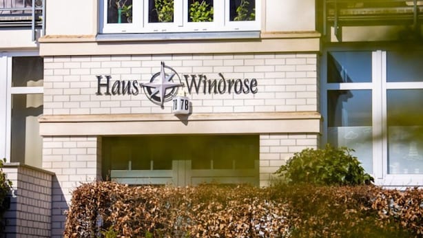 Ein Gebäude mit der Schilderung "Haus Windrose" und der Hausnummer 18.