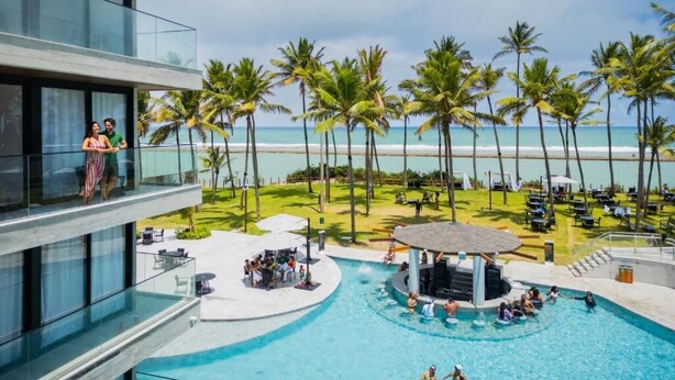 Un hôtel moderne doté d’une piscine, de palmiers et offrant une vue sur la plage.