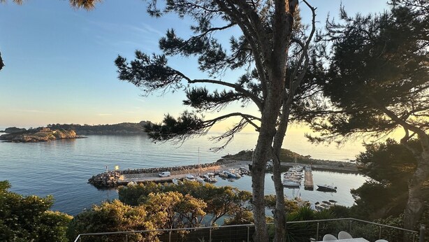 En uteplats med utemöbler, utsikt över havet och en brygga med båtar.