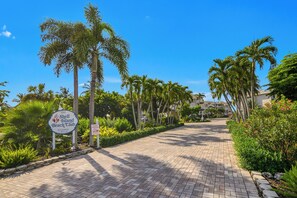 Un sendero pavimentado que conduce a un edificio con un letrero que dice Shell Island Beach Club.