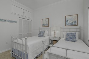 Un dormitorio con dos camas, una mesita de noche, una lámpara y un cuadro enmarcado.
