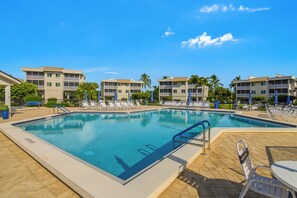 A swimming pool with lounge chairs and a clear blue sky.