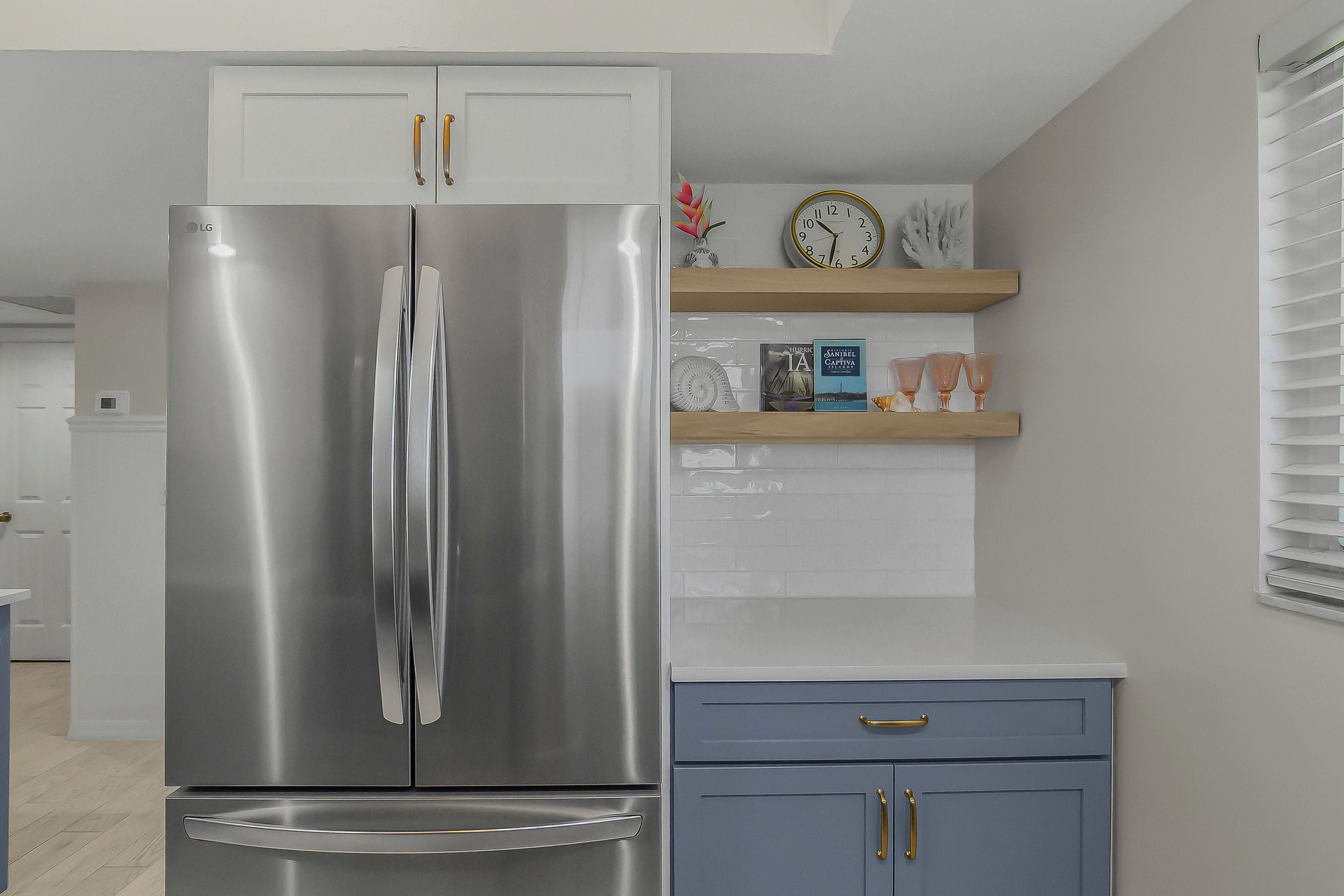 A kitchen with a stainless steel refrigerator, a blue cabinet, and a clock on the wall.