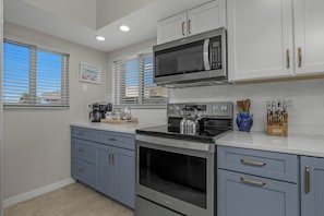 A modern kitchen with a built-in microwave, oven, and kettle.