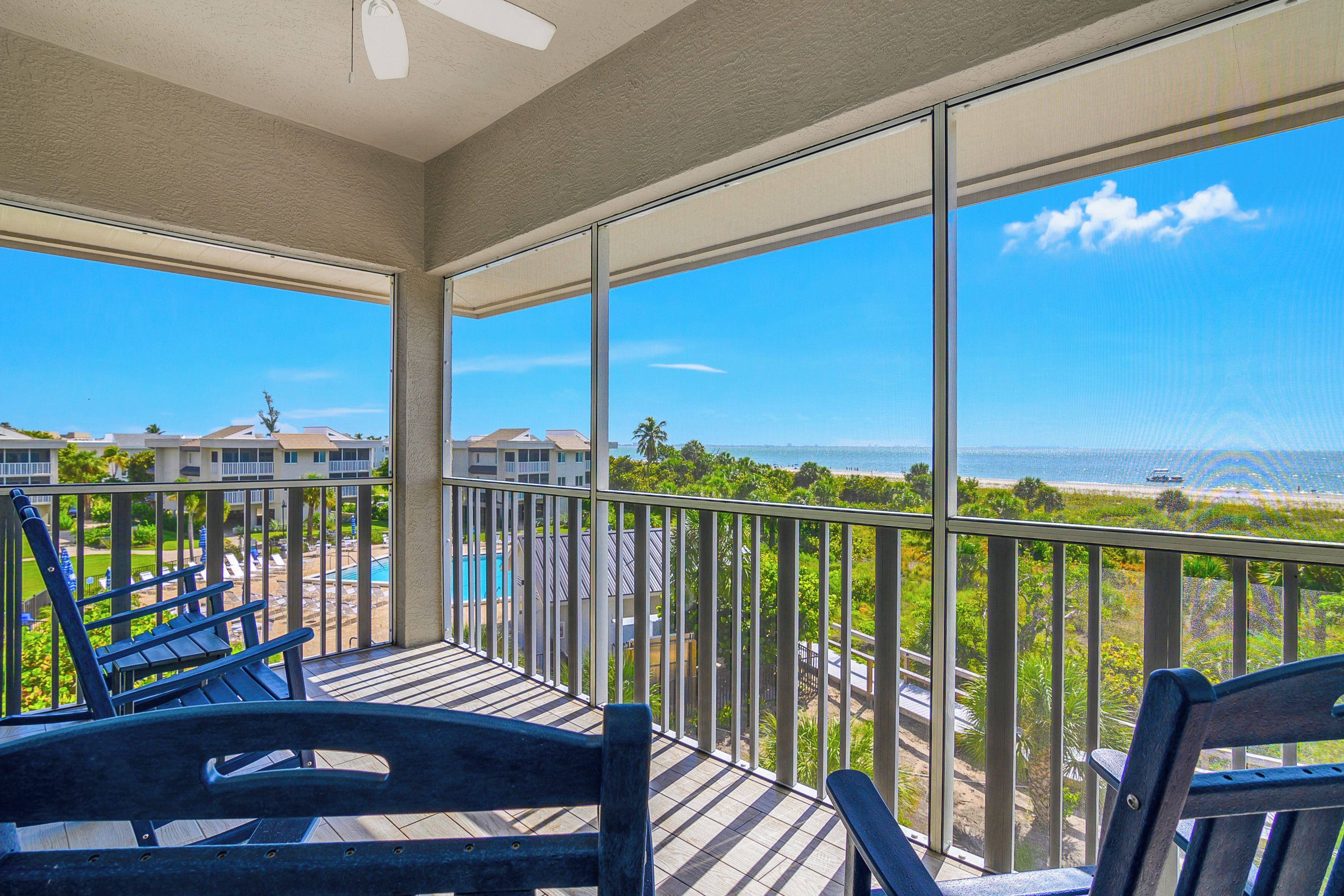 A balcony with a view of a swimming pool and a beach.