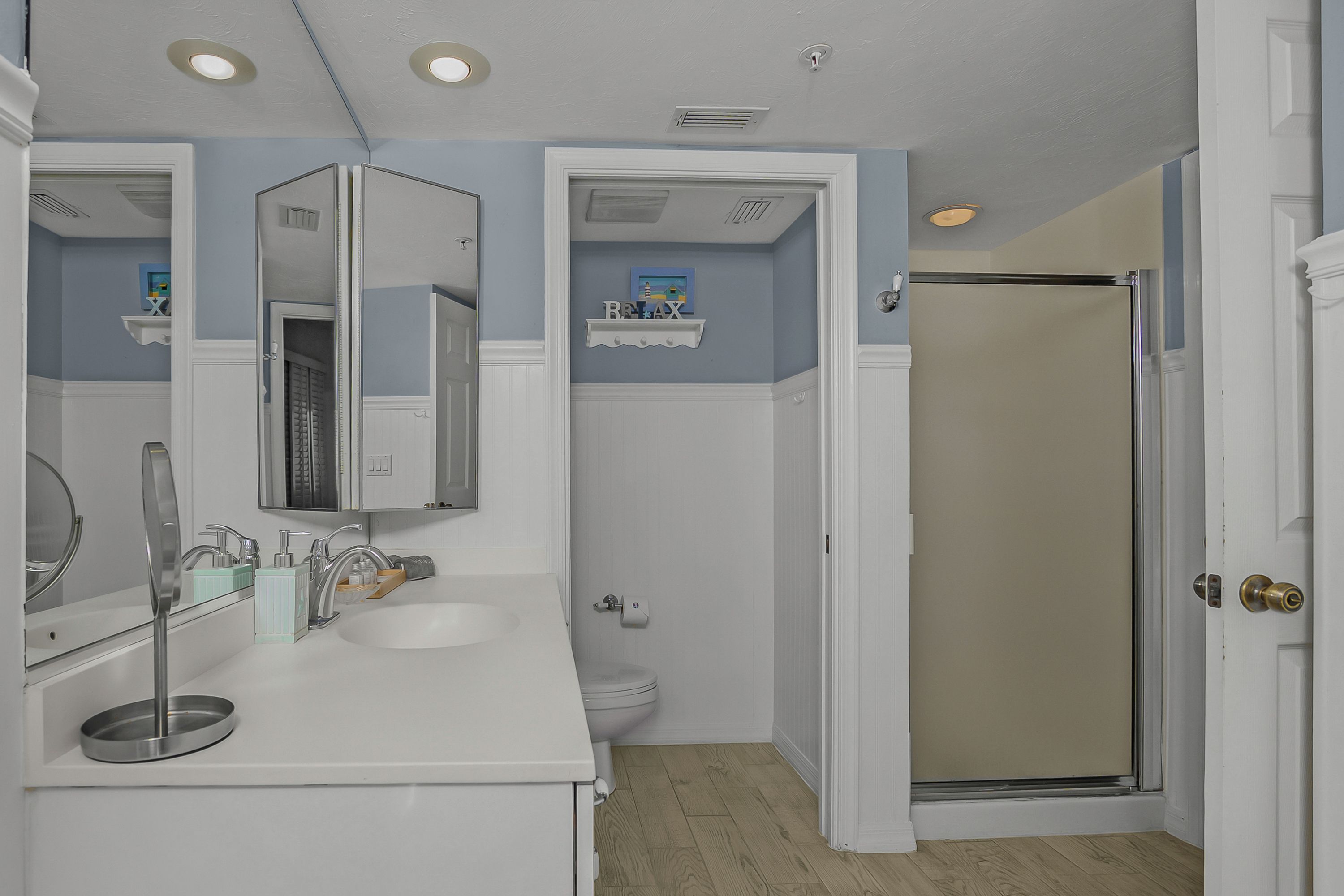A bathroom with a white vanity, a toilet, and a shower door.