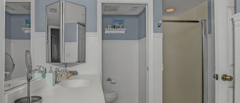 A bathroom with a white vanity, a toilet, and a shower door.