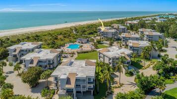 A resort with multiple buildings, a swimming pool, and a beach view.