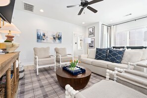 A modern living room with a round coffee table, two armchairs, a sofa, and a ceiling fan. - Lonestar on the Plains  Designer 3BR Cottage Pet Friendly Close to Campus (Auburn)