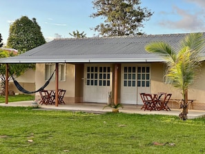 A house with a covered patio, two doors, and a small garden with a palm tree. - Casa Novo Airão Espaço com dois chalés (Novo Airão)