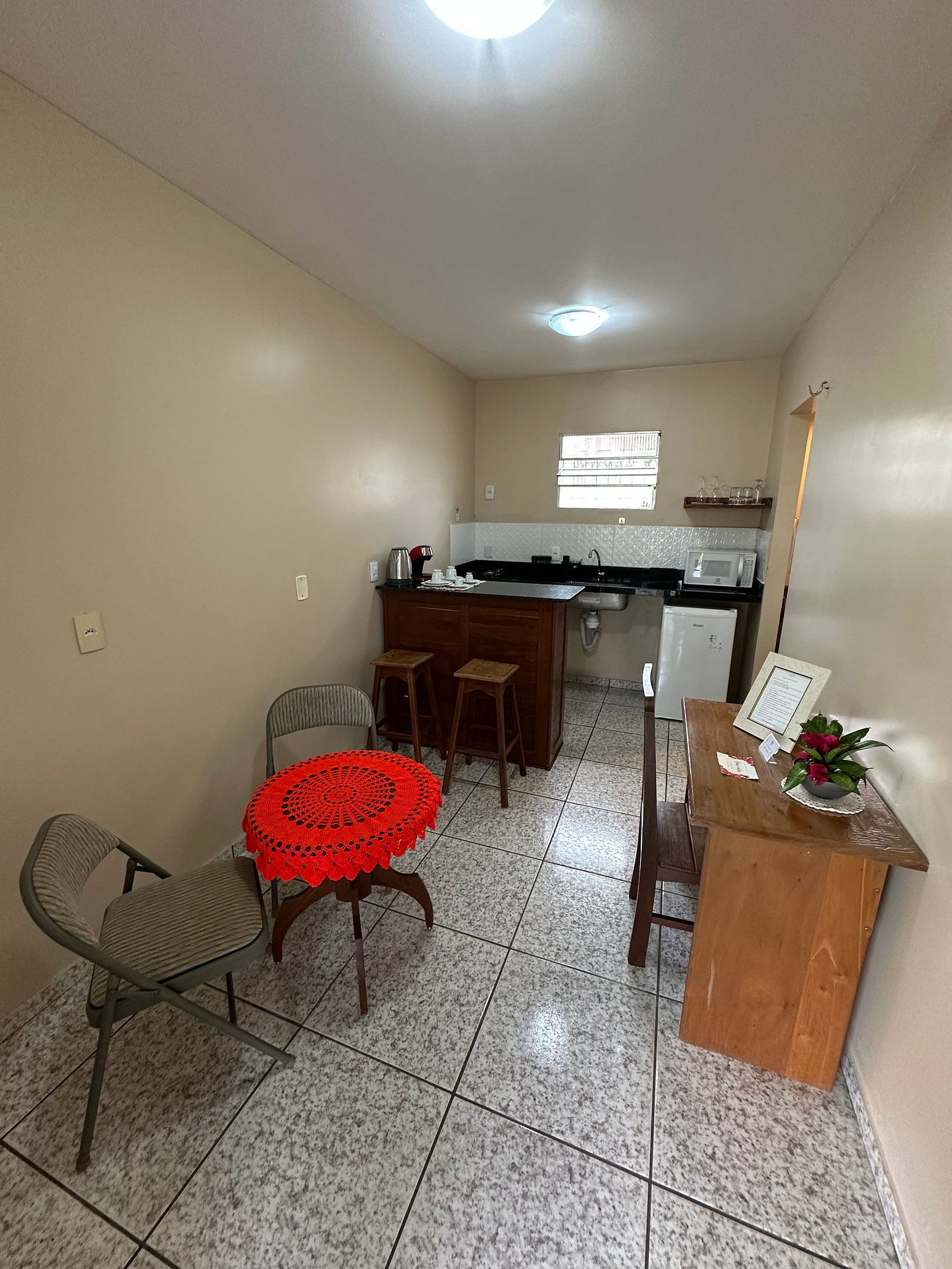 A compact kitchen with a dining area, a small refrigerator, and a window providing natural light.