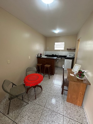 Cozinha compacta com área de refeições, pequena geladeira e janela que proporciona iluminação natural.