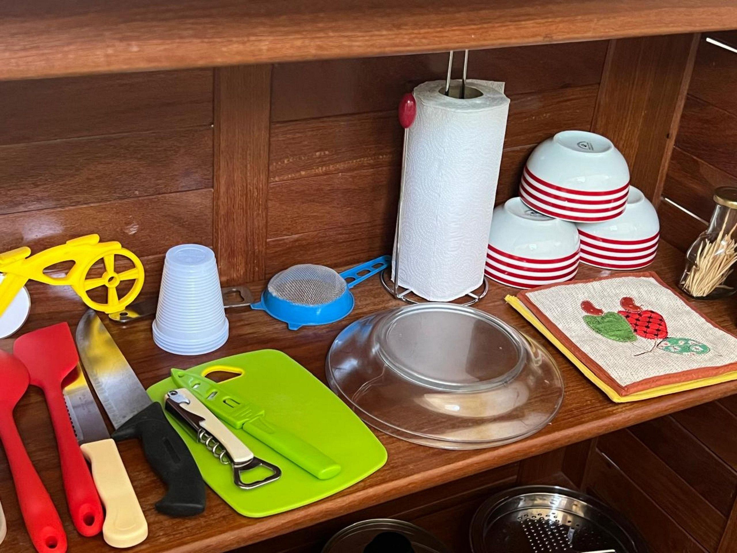 A kitchen counter with various utensils, a cutting board, a paper towel holder, and stacked dishes.