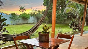 A wooden outdoor dining set with a table and chairs, a hammock, and a potted plant. - Casa Novo Airão Espaço com dois chalés (Novo Airão)
