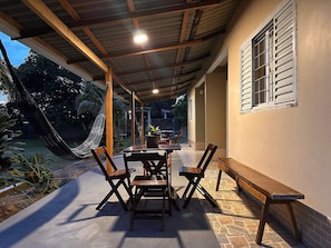 A covered patio with a table and chairs, a hammock, and a view of the outdoors. - Casa Novo Airão Espaço com dois chalés (Novo Airão)