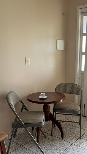 Ein Zimmer mit einem runden Tisch, zwei Stühlen, einer Tür und einem Lichtschalter an der Wand.