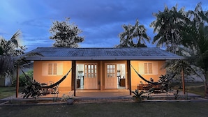 A two-story building with a tiled roof, a front porch, and a hammock. - Casa Novo Airão Espaço com dois chalés (Novo Airão)