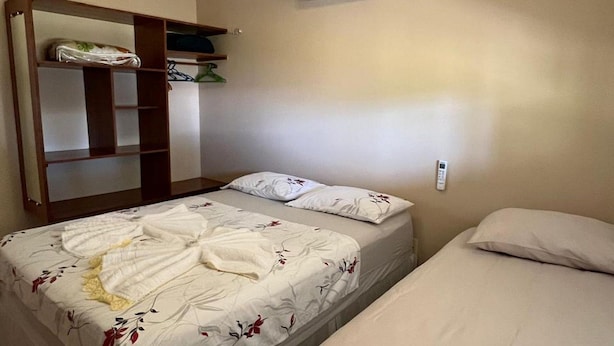 A bedroom with two beds, a wardrobe, an air conditioning unit, and a bedside telephone. - Casa Novo Airão Espaço com dois chalés (Novo Airão)