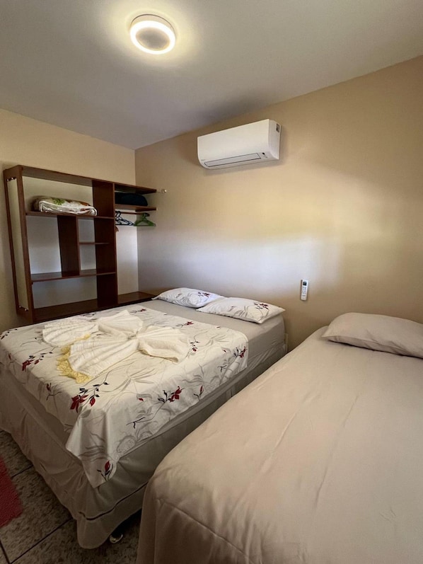 A bedroom with two beds, a wardrobe, an air conditioning unit, and a bedside telephone. - Casa Novo Airão Espaço com dois chalés (Novo Airão)