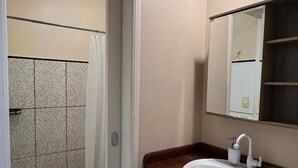A bathroom with a shower, a sink, and a mirror. - Casa Novo Airão Espaço com dois chalés (Novo Airão)