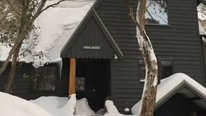 A dark wooden building with a sign reading "HIGHLANDER" at the entrance. - Highlander - Dinner Plain (Dinner Plain)