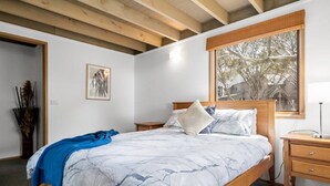 A bedroom with a bed, wooden headboard, bedside tables, a window with a view, and a framed picture on the wall. - Frankies - Dinner Plain (Dinner Plain)