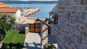 Una propiedad costera con un muro de piedra, un portón de madera y vistas al mar.